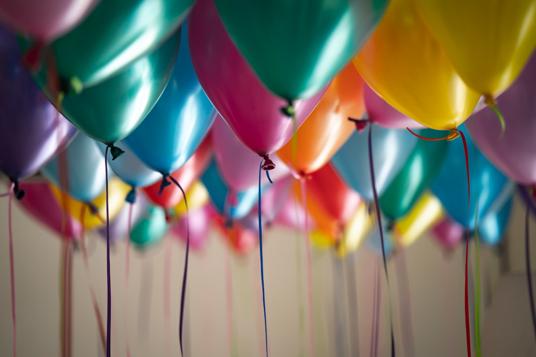 Ballons multicolores suspendus au plafond avec des rubans, dans une ambiance de fete d'anniversaire.